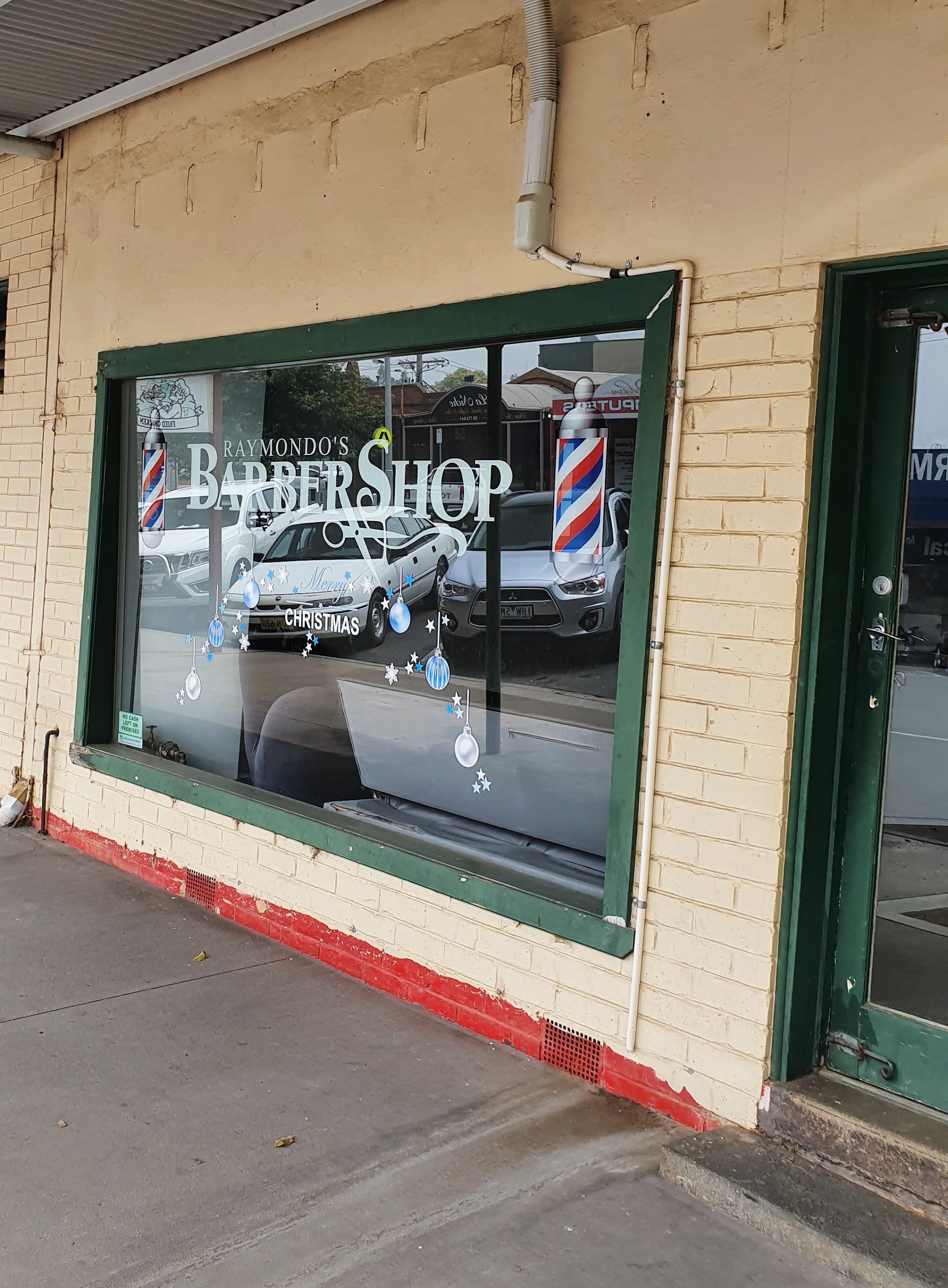 Raymondo’s Barber Shop front window with green timber frame and barber pole decals